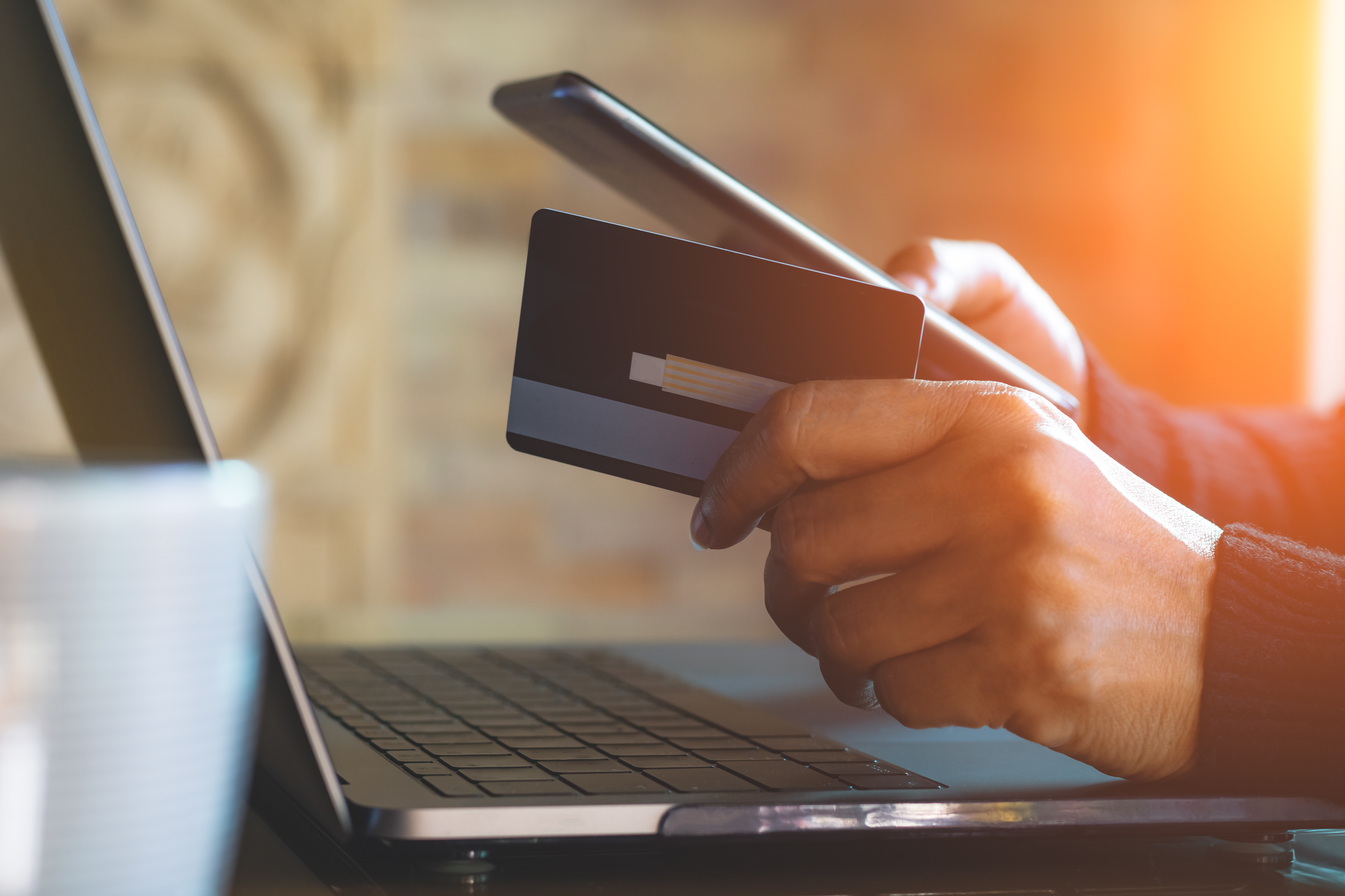 Person holding credit card at laptop