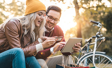 Young couple paying with debit card on tablet