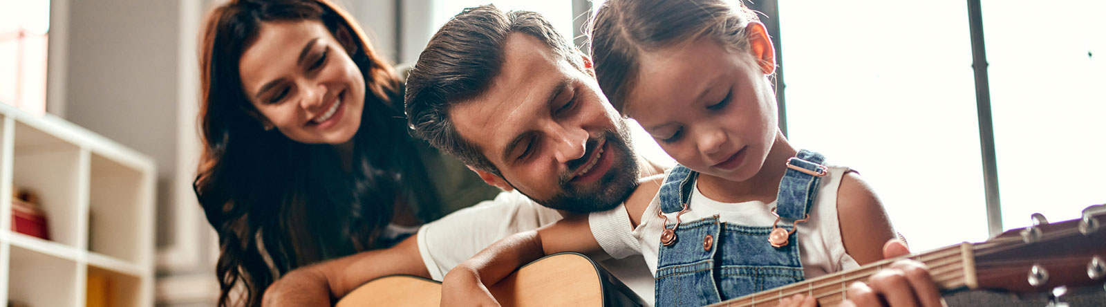 Young family playing guitar in living room